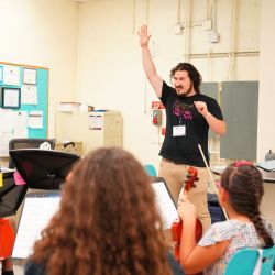 Alejandro Garcia, Teaching Artist from Young Musicians of Alamance, inspires beginning strings students during a vibrant training session with TATI. Photo Source: TATI.